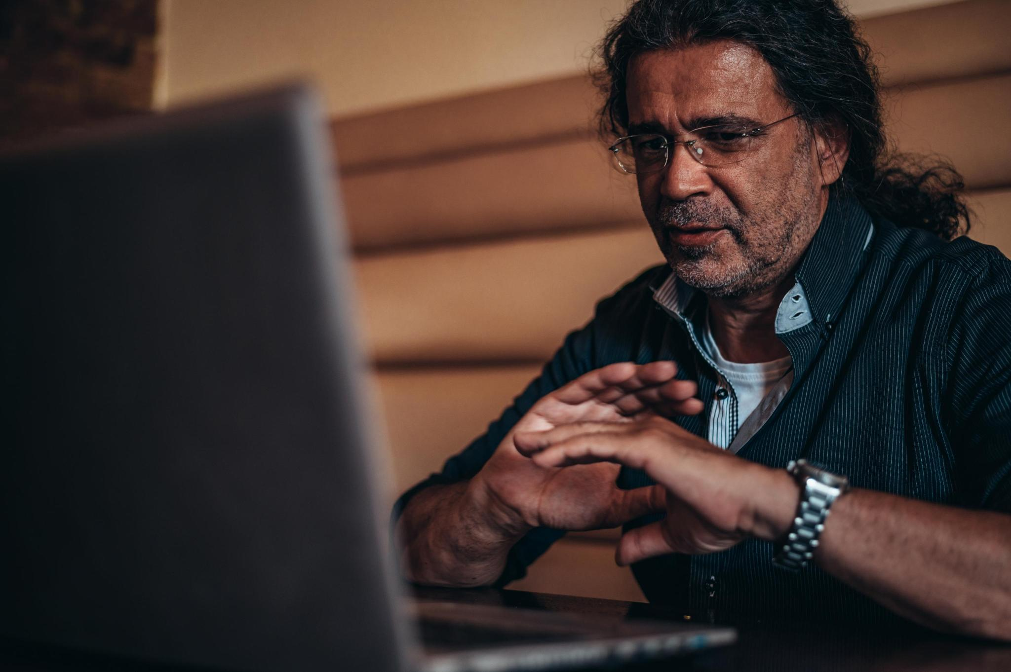 A middle-aged man in glasses reviewing information on a laptop at home
